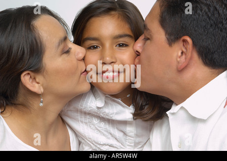 Hispanic Eltern küssen Tochter Wangen Stockfoto