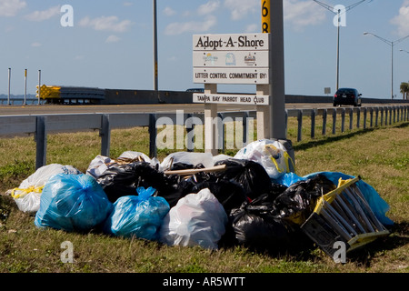 Taschen von Müll rund um ein Straßenschild Cleanup Stockfoto