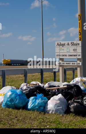 Taschen von Müll rund um ein Straßenschild Cleanup Stockfoto