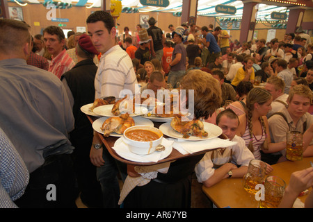 Server-Kellnerin tragen Tablett mit Brathähnchen oder gebratenem Fleisch um im Bierzelt auf Oktoberfest Bier Festival Stockfoto