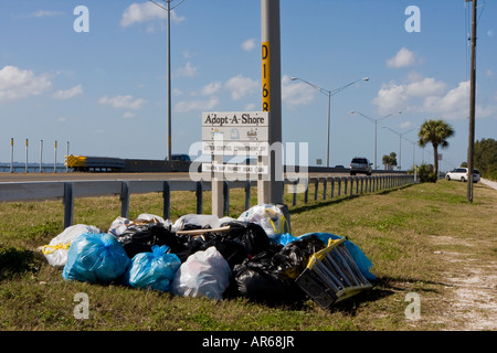 Taschen von Müll rund um ein Straßenschild Cleanup Stockfoto