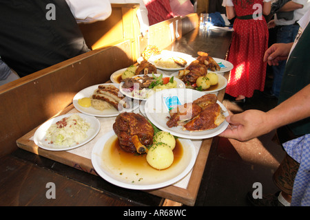 Server-Kellnerin tragen Tablett mit Brathähnchen oder gebratenem Fleisch um im Bierzelt auf Oktoberfest Bier Festival Stockfoto