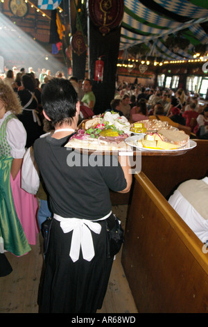 Server-Kellnerin tragen Tablett mit Brathähnchen oder gebratenem Fleisch um im Bierzelt auf Oktoberfest Bier Festival Stockfoto