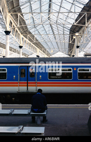 Mann sitzt im Bahnhof Stockfoto