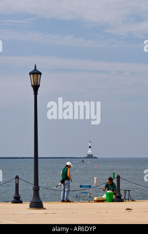 Fischer in Conneaut Park mit Conneaut West Breakwater Leuchtturm in der Ferne auf dem Eriesee Conneaut Ohio Stockfoto