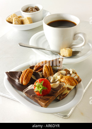 Schokolade wirbelt Quadrate mit frischen Erdbeeren und Pekannüssen auf einem Tablett mit schwarzen Kaffee. Stockfoto