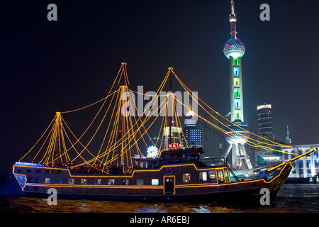 Ein beleuchtetes Schiff schwimmt auf dem Huangpo-Fluss in der Nacht. Flusskreuzfahrten sind beliebt bei den Touristen in Shanghai. Stockfoto