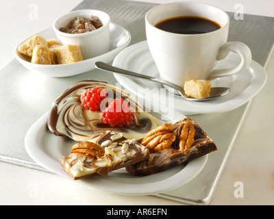 Weiß, unbedruckt und Milch Schokolade marmoriert Swirl mit frischen Erdbeeren und Pekannuss auf einem Tablett mit schwarzem Kaffee. Stockfoto