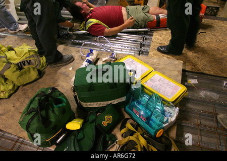 Ein Mann mit einem Bein zerquetscht durch fallende Stahlträger von einer Baustelle in einen Krankenwagen durch Sanitäter, London verschoben werden. Stockfoto