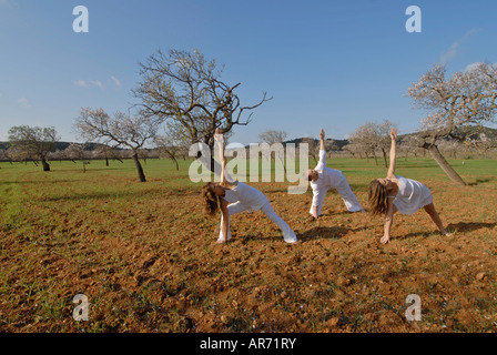 Herr drei Menschen, ein Schwedisch-Mann, eine Brasilianerin und eine Spanierin, üben von Yoga in den Bereichen von Ibiza, Spanien Stockfoto