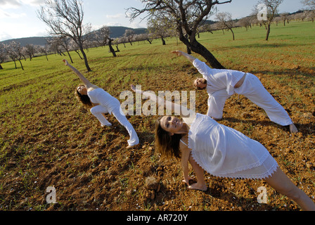 Herr drei Menschen, ein Schwedisch-Mann, eine Brasilianerin und eine Spanierin, üben von Yoga in den Bereichen von Ibiza, Spanien Stockfoto