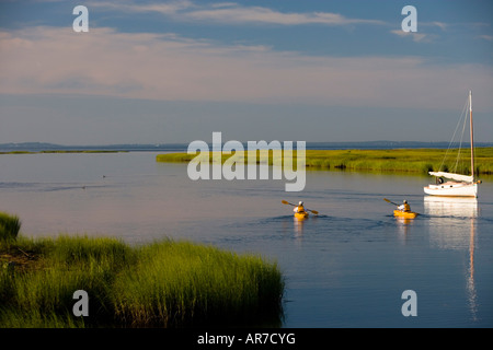 Kanuten paddeln vorbei an einem Segelboot vor Anker zwischen Great Island und der Küste in Old Lyme in Connecticut River Stockfoto