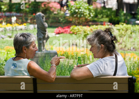 Zwei Reife Frauen im Park haben ein lebhaftes Gespräch schönen Blumengarten Stockfoto