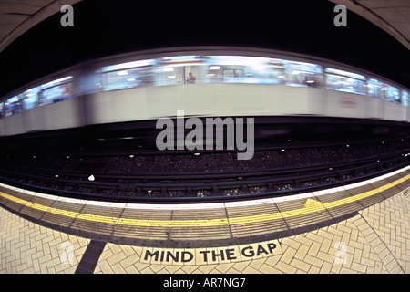 District Line u-Bahn vorbei an einer Plattform in London. Fotografiert mit einem Fisheye-Objektiv. Stockfoto