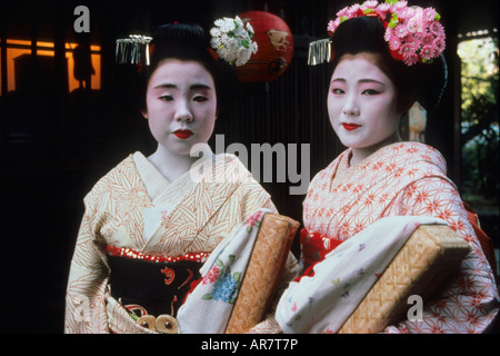 Zwei Auszubildende Geishas, bekannt als "Maikos" zur Arbeit durch die Straßen des Kyoto-Protokolls in der Abenddämmerung Fuß. Stockfoto