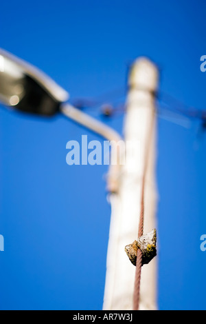 Links hinter auf einem rostigen Kabel an einen Laternenpfahl vor blauem Himmel. Straßenlaterne. Stockfoto