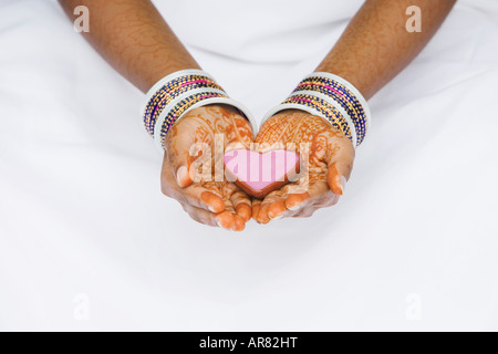 Inderin mit Henna Händen hält rosa Herz geformt Gericht. Indien Stockfoto