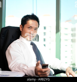 Geschäftsmann, sitzen im Büro, mit einem Mobiltelefon Stockfoto