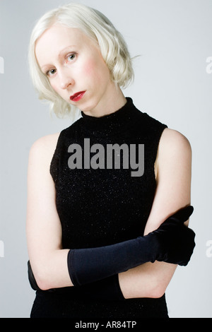Farbe Porträt eine blonde Frau in einem schwarzen Kleid und schwarzen Handschuhen, mit ihren verschränkten Armen stehen. Stockfoto