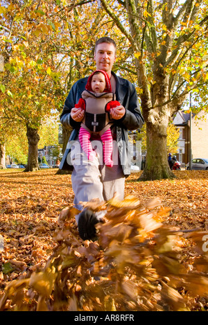 Ein Vater und ein Baby genießt, zu Fuß durch farbenfrohe Herbst Blätter auf Clapham Common in London, England, UK Stockfoto