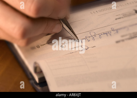 eine Nahaufnahme von einem Womans Hand und Stift schreiben, einen Scheck Stockfoto