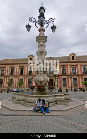 Paar Touristen sitzen auf den Stufen des alten Brunnen mit Laternenpfahl, Sevilla; Andalusien; Spanien; Stockfoto