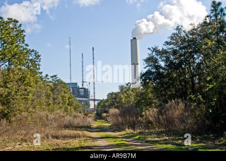 Schornstein eines Kraftwerks Aufstoßen weißer Rauch am Ende eines Feldwegs. Stockfoto