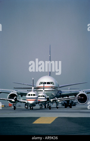 Boeing 767 Jet Airliner und Jetstream Turbo prop zweistrahligen Regionalflugzeuge Rollen in einer Warteschlange zum Abheben der verschiedenen Größen warten Stockfoto