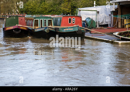 Schmale Boote fast über ihre Liegeplätze auf einer überfluteten Wey Navigation in Guildford, Surrey, England. Stockfoto