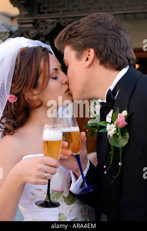 Glückliche junge Brautpaar küssen und gegenseitig mit Champagner zu toasten. Stockfoto