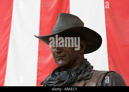 Statue von John Wayne gegen amerikanische Flagge am John Wayne Flughafen Stockfoto