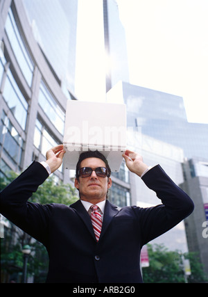 Geschäftsmann, Laptop-Computer über Kopf halten Stockfoto