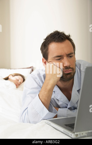 Mann mit Laptop im Bett Stockfoto