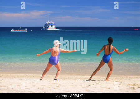80 Jahre alte Großmutter und 40 jährige Mutter tun Yoga zusammen am Strand in Mexiko Stockfoto