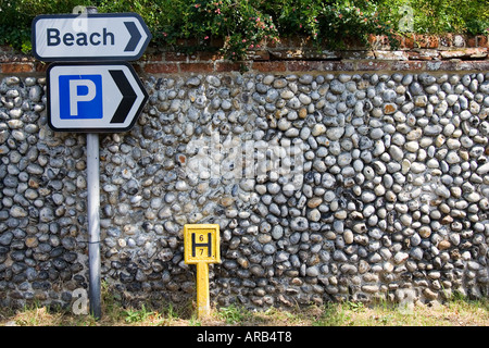 Parkplätze und zum Strand Wegweiser und Hydranten von Ziegel und Feuerstein wall Happisburgh Norfolk UK Stockfoto