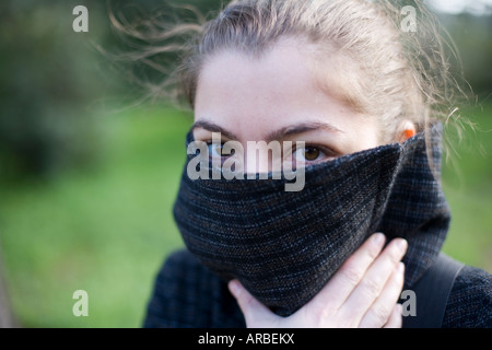 Porträt einer jungen Frau, die über ihr Gesicht darauf hindeutet, dass sie einen arabischen Schleier trägt die Hälfte Stockfoto