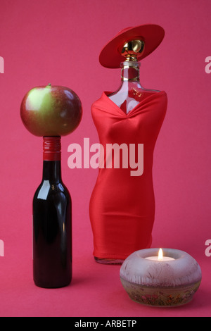 Der erste Tag. Allegorische Komposition von Mann und Frau. Stillleben mit Flaschen, Apfel und Tee Kerze anzünden. Künstlerische Vision. Stockfoto