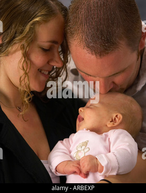 Eine Mutter, Vater und Kind Babymädchen mit Papa das Baby küssen Stockfoto