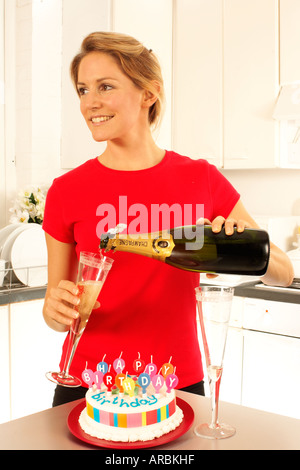 MÄDCHEN MIT CHAMPAGNER UND GEBURTSTAGSKUCHEN Stockfoto