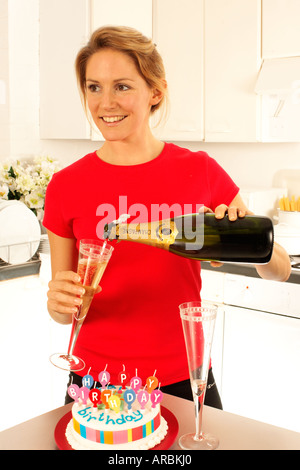 MÄDCHEN MIT CHAMPAGNER UND GEBURTSTAGSKUCHEN Stockfoto