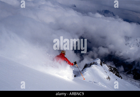 Männlichen Skifahrer auf tiefen unberührten Schnee Skifahren durch die Wolken hoch in den Bergen Chamonix Frankreich Stockfoto