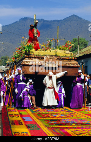 Männer tragen eine riesige hölzerne Schwimmer Christi über farbige Sägemehl Teppich während der Osterprozession in Antigua, Guatemala Stockfoto