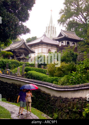 Japan Hirado Insel Paare, die Gasse im Regen mit St. Francis Xavier-Gedächtnis-Kirche im Hintergrund Stockfoto