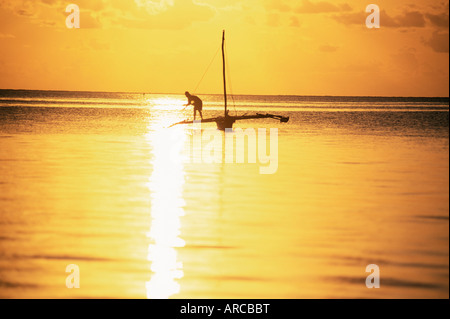 Ausleger-Kanu und Fischer in der Silhouette bei Sonnenaufgang Jambiani, Sansibar, Tansania, Ostafrika, Afrika Stockfoto