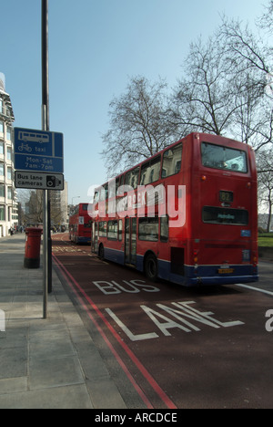 London Park Lane 2 Busse mit Geschwindigkeit in breite Spur vorbeifahrenden Bus Bushaltestelle alle im roten Asphalt abgesteckt Stockfoto