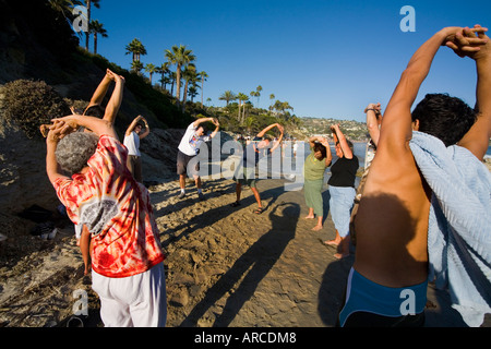 Mitglieder der einen Lachclub Yoga tun vorbereitenden Turnübungen am Meer in Laguna Beach CA erfüllen Stockfoto