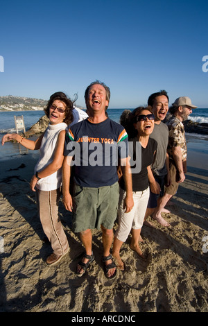 Der Wassertruppführer einen Lachclub Yoga setzt ein Beispiel für seine Mitglieder, wie sie am Meer erfüllen Stockfoto