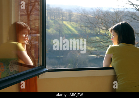 Junge Frau, Blick aus dem Fenster auf einen Blick auf die Landschaft - spiegelt sich in dem Glas, Rückansicht Stockfoto