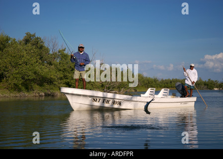 Ein Fliegenfischer fängt ein Tarpon, während es in von der Wohnungen Boot beim Fliegenfischen auf Isla Holbox Mexiko springt Stockfoto