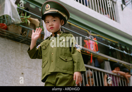 Ein junges Mädchen gekleidet wie ein Volk Befreiung-Armee-Soldaten oder Polizisten in einer Parade am Cheung Chao Bun Festival durchgeführt wird Stockfoto